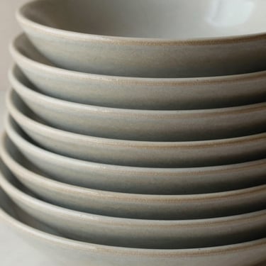 Close-up of stacked ceramic dinnerware in neutral slate tones, clean daylight, architectural composition