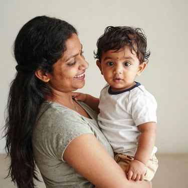 Smiling mother holding her chubby toddler in a bright hospital waiting area.