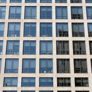 Crisp architectural photography of a modern high-rise building facade in New York City, bright natural daylight, cool blue tones, sharp focus, 35mm lens.