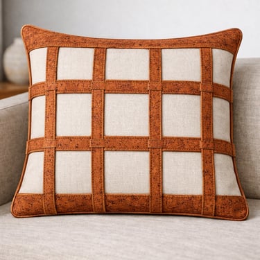 Modern cream linen throw pillow with a decorative brown cork grid pattern on a beige sofa.
