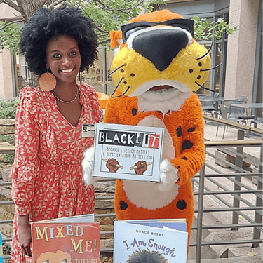 Vendor at Frito Lay campus selling books beside Chester Cheetah, the Frito-Lay mascot, at the ERG Summit vendor fair.