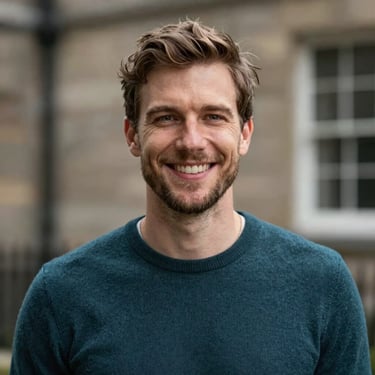 A portrait of a smiling British / UK travel creator in a smart-casual dark teal sweater.