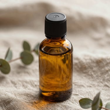 Extreme close-up of a warm amber oil bottle resting on a natural linen cloth, soft morning light, botanical sprigs.