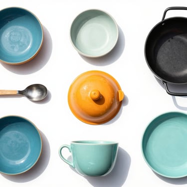 Top-down flat lay of modern home goods and kitchen accessories, bright high-key retail photography, clean natural daylight, crisp shadows