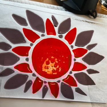 Purple and orange fused-glass sunburst on clear background