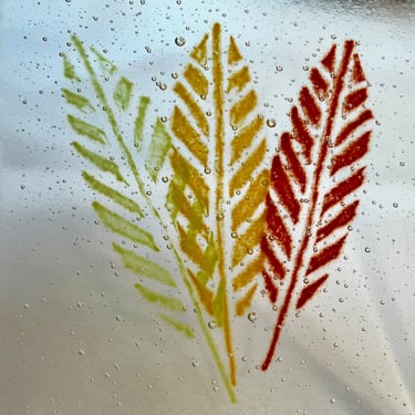 Red, orange and green glass powder sifted through a screen onto glass and kiln fired