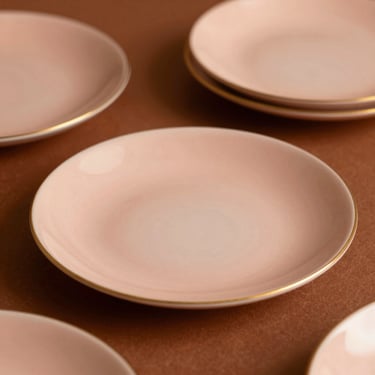 Delicate porcelain side plates with soft gold rims, warm side lighting