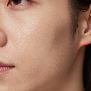 Macro close-up of unretouched skin showing natural texture, fine lines, and uneven tone under neutral clinical lighting, sharp focus.