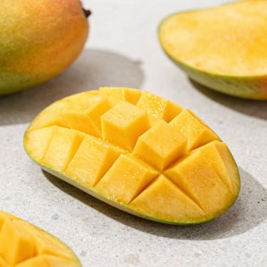 Macro shot of fresh ripe mango slices on a clean stone counter, bright daylight, rich golden hues, crisp focus.