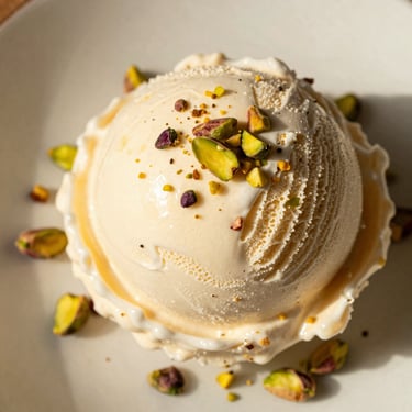 Overhead macro shot of a slice of Maraş ice cream served on a plate with crushed pistachios, warm side-light