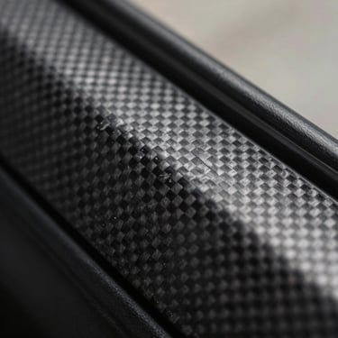 Macro shot of carbon fibre textured protective film on door trim, weave pattern, technical luxury aesthetic.