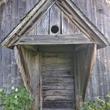 Historic 200-year-old board farmhouse with an original unpainted wood entrance and traditional wood siding.