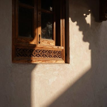 Close-up of hand-carved cedar wood details and warm plaster in a Marrakech riad, soft morning light, architectural digest style.