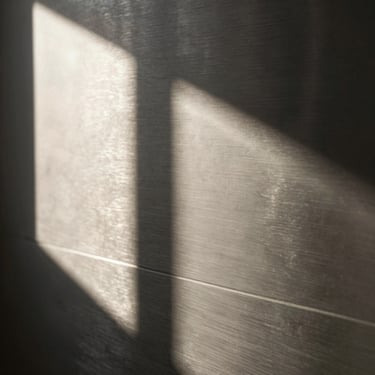 Extreme close-up of brushed surgical steel texture, hard dramatic studio shadows