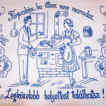 Kék fonallal hímzett falvédő idézettel két alakkal konyha háttér.