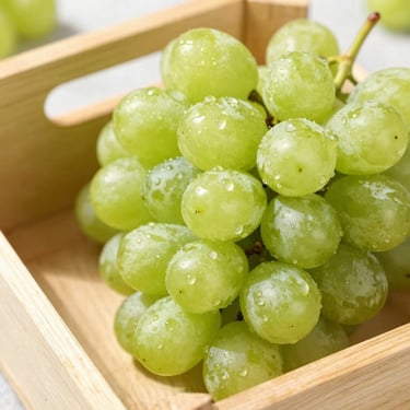 Close-up of fresh green seedless grapes in a wooden crate, bright natural daylight, water droplets visible