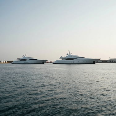 Cinematic wide-angle of an architectural marina at overcast daylight, a custom superyacht moored in the distance, generous negative space.