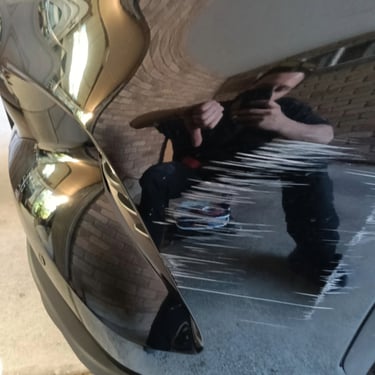 Close-up of deep white scratches and paint damage on a black car bumper and side panel.