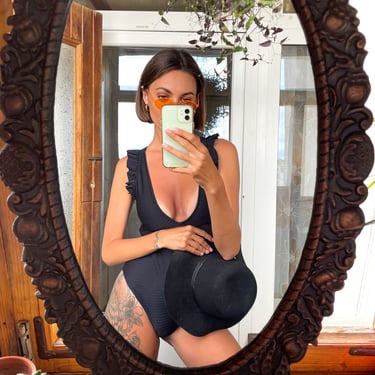 Mujer viste elegante viste bikini negro frente a un espejo moda internacional