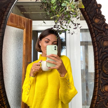 Mujer viste elegante viste suéter amarillo frente a un espejo moda internacional
