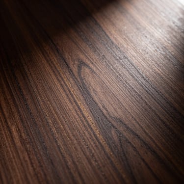 Extreme close-up of dark walnut veneer with golden grain lines, dramatic spotlighting