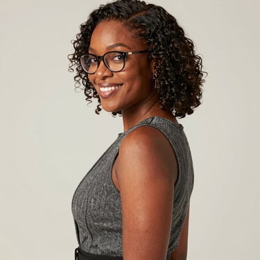Smiling woman working on a laptop in a modern office environment.
