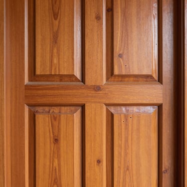 Close-up of a wooden door with a rich, glossy wood polish finish, showing natural grain, bright indoor light, Ahmedabad.