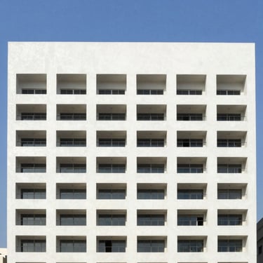 Large commercial building facade with a fresh, uniform paint job, clear blue sky, professional appearance, Ahmedabad.