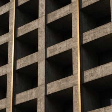 Abstract geometric architectural detail of concrete and gold-toned steel lines, high contrast shadows, low-key lighting.