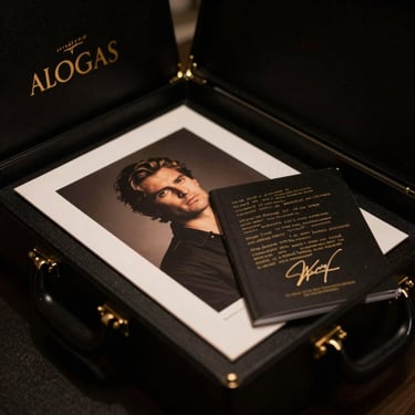 A luxury obsidian black collector box with embossed gold lettering, containing art prints and a signed lyric book, cinematic lighting, 35mm film