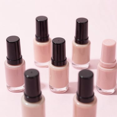 Sleek product bottles of nail dehydrator and primer arranged neatly on a pale blush surface, high-key beauty photography