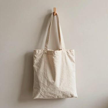A heavy canvas tote bag hanging on a simple wooden peg, soft morning light