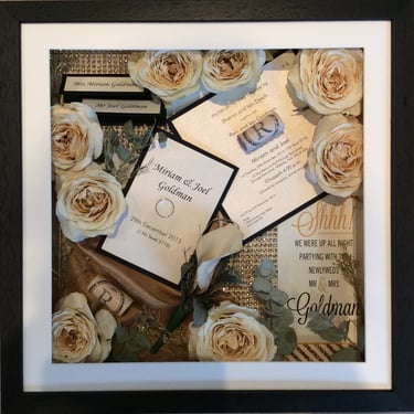 memory box full of wedding items, invitations and preserved wedding bouquet flowers in a deep frame