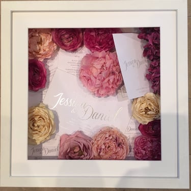 memory box full of wedding invitations and preserved wedding bouquet flowers in a deep frame