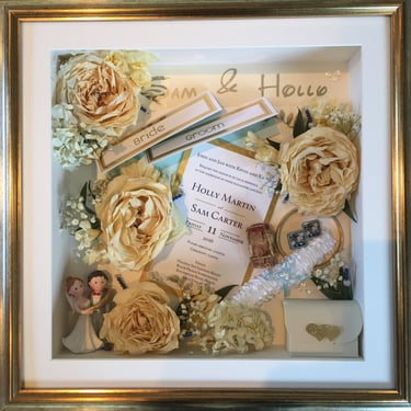 memory box full of preserved wedding flowers, place names, cake topper menus and garter
