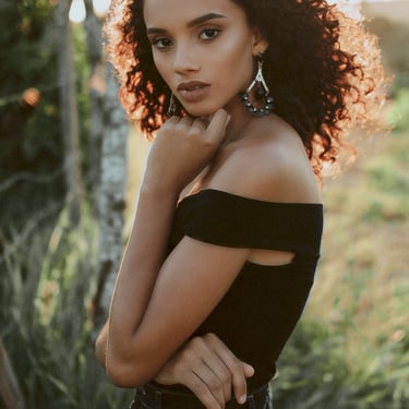 a woman with curly hair and earrings on her neck