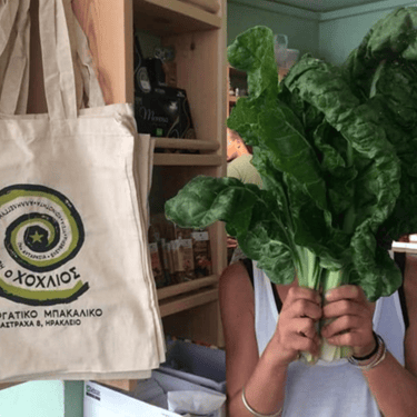 Cretan vegetable shop with a woman holding fresh lettuce