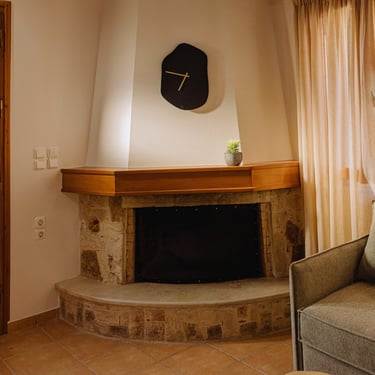 Cozy, stone fireplace at Tonia's Cottage, with a black clock on the wall