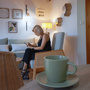 A woman checking her phone while enjoying a cup of coffee at Tonia's Cottage