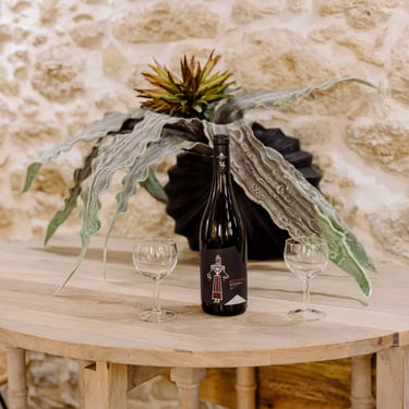 Wine with two glasses on a table, surrounded by a beautiful stone wall and floral decorations