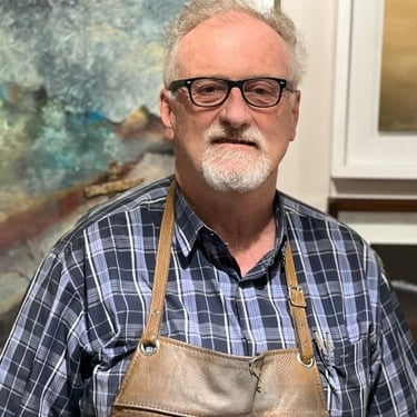 Portrait of Simon Shone, South African sculptor and master goldsmith, wearing a leather apron in his studio