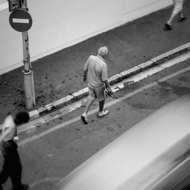 Elderly man walking past a no-enty sign on a quiet Cape Town street, captured in black-and-white fine art style.