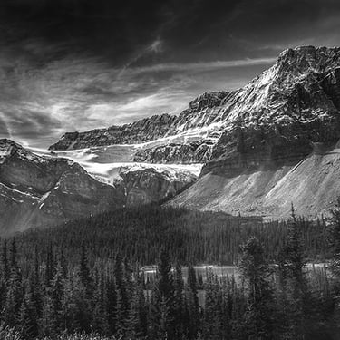 Dramatic black and white photo of rugged snowy Canadian Rocky Mountains overlooking river valley