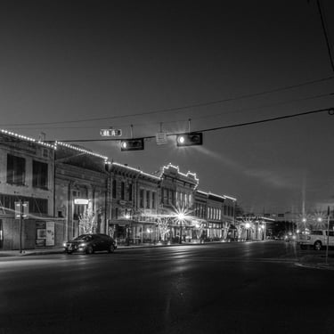 Night photo of Austin Ave in Georgetown, Texas, with it's historic buildings illuminated by streetlights