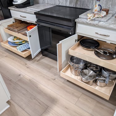 Two kitchen cabinets are open with glide out shelves extended out and filled with pots, pans and dishes. Better use of space!