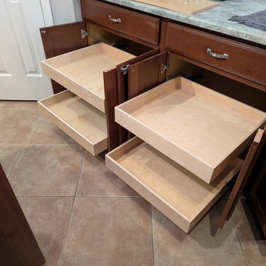 Four empty rolling shelves are shown a kitchen cabinet after installation.
