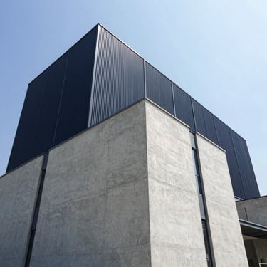 Low-angle heroic perspective of a completed modern industrial facility with clean concrete and steel facades, bright daylight.