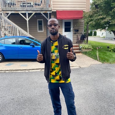 a man in a yellow shirt and jeans standing in front of a house