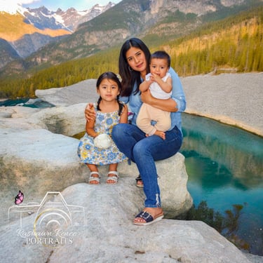 a woman sitting on a rock with her two children for a family portrtait session