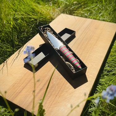 Knife in a box on a cutting board surrounded by gras